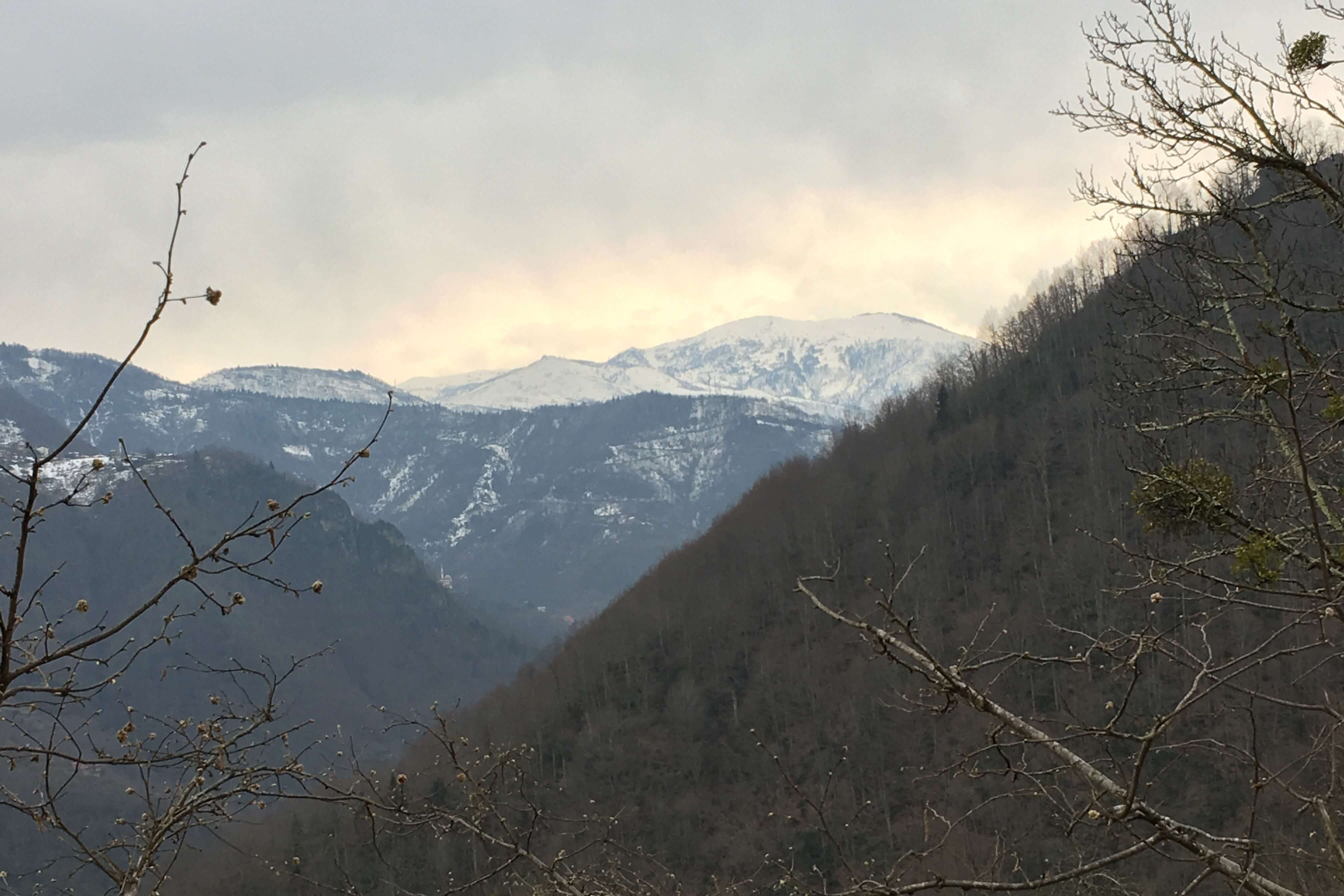 sun breaking through the clouds over snowcapped mountains